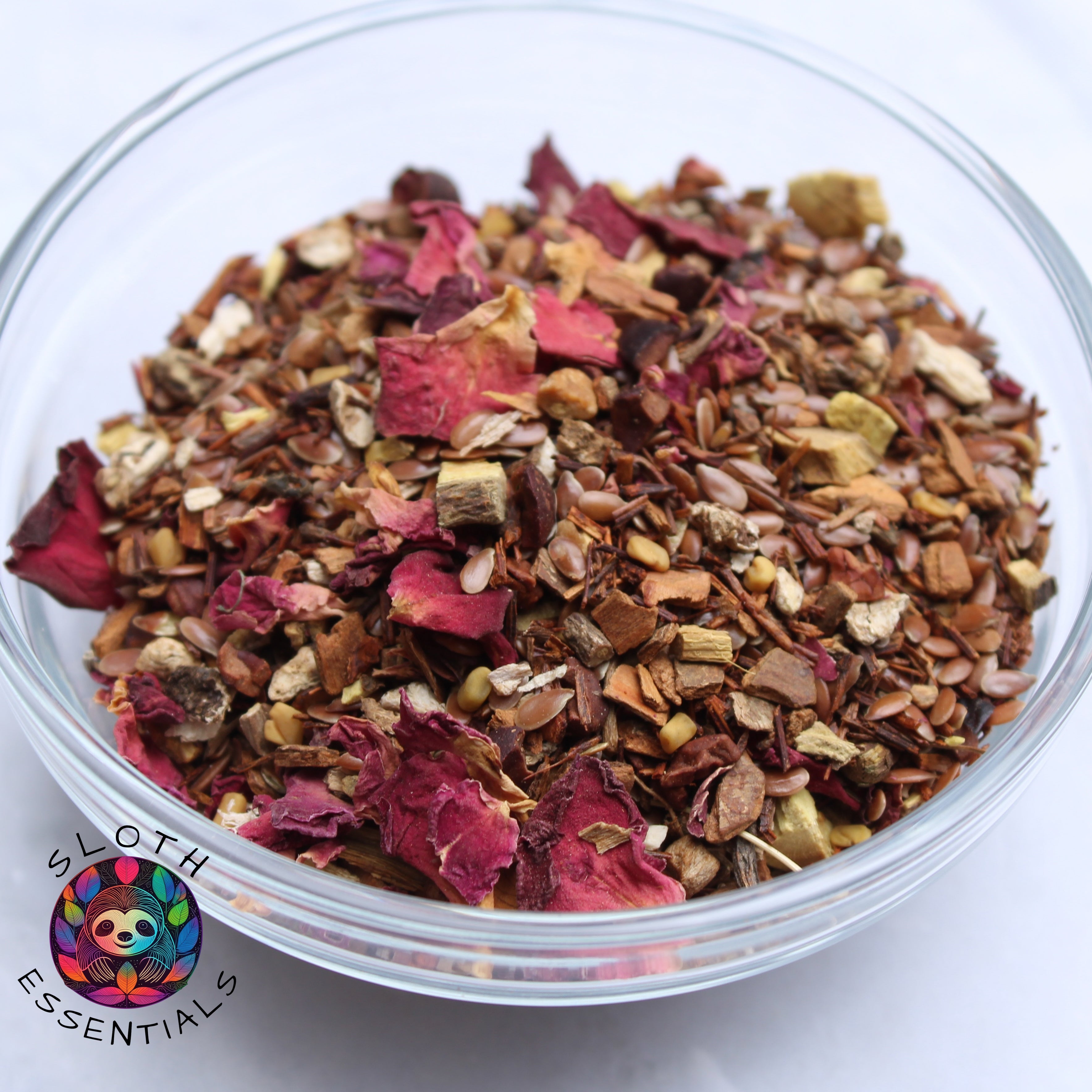 Colon Cleanse Tea in a glass bowl, featuring vibrant colors and ingredients like flaxseed, rooibos leaf, cinnamon, dandelion root, licorice root, cacao nibs, fenugreek seed, and rose petals