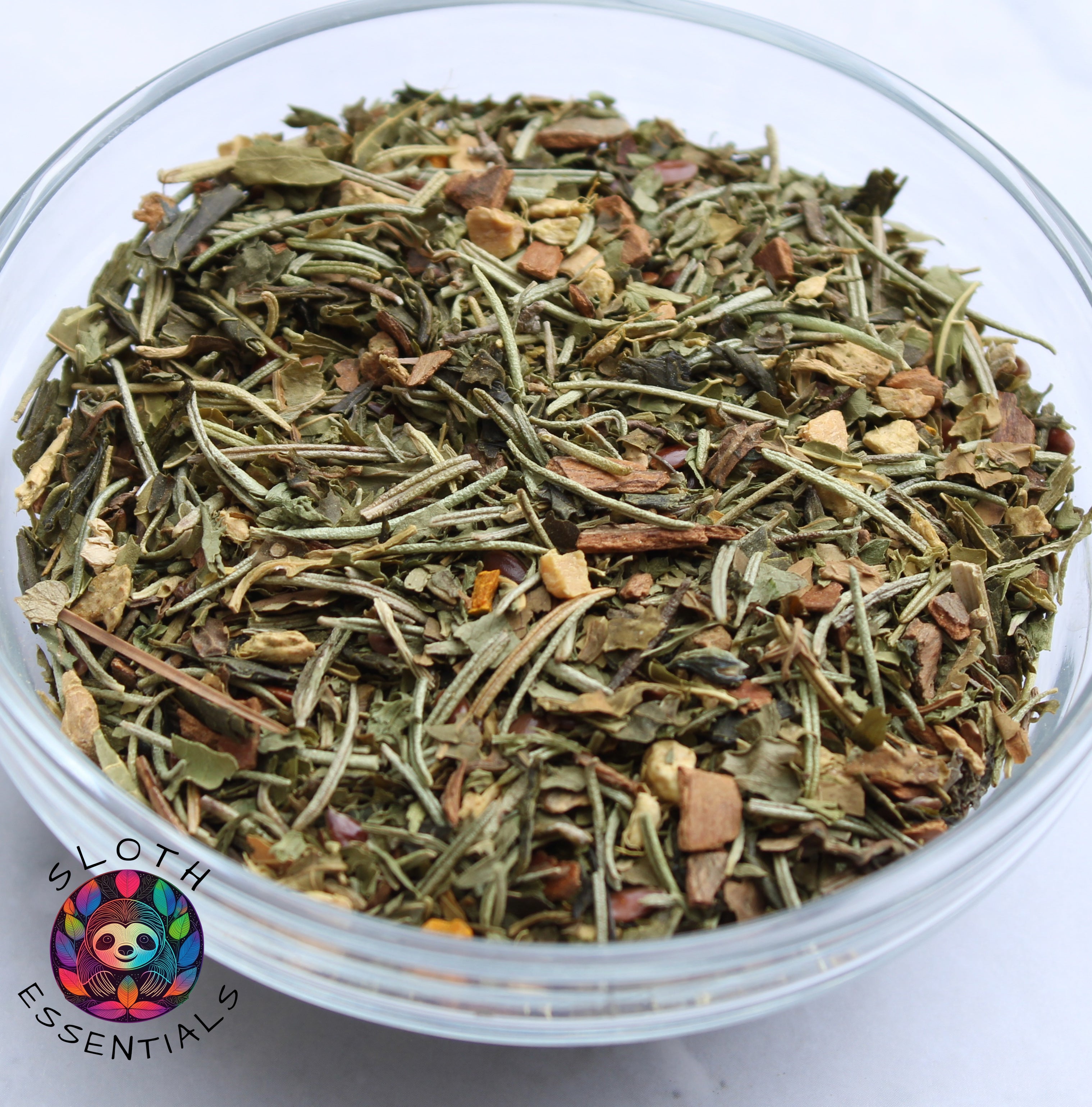 Focus Blend Tea in a glass bowl, featuring a close-up view of ingredients like rosemary, ginger, cinnamon, parsley, papaya leaf, sencha green tea, flax seed, and turmeric.